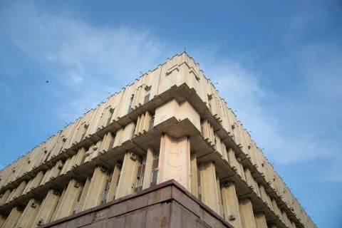 A corner of concrete building bottom view on background of blue sky with clou Stock Photos