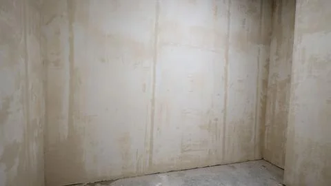 Corner of empty room with freshly plastered walls and concrete floor during.. Stock Photos