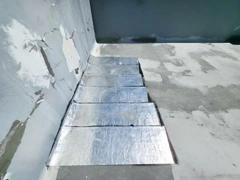 Corner of a flat rooftop under repair with silver waterproofing membrane sh.. Stock Photos