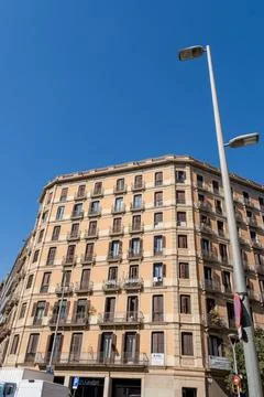 Corner hotel facade stands in bright sun, showing rows of balconies, closed.. 库存照片