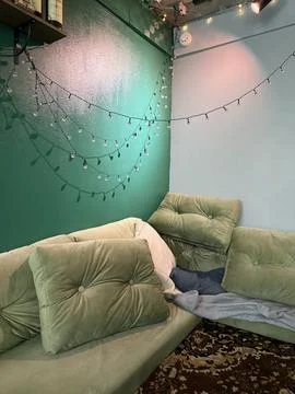 A corner interior with a soft green cushioned sofa Stock Photos