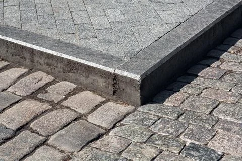 Corner of a pedestrian sidewalk made of stone rectangular brick tiles. Stock Photos