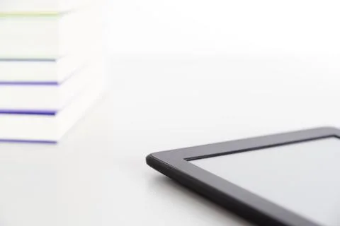 Corner of a stack of books and an electronic reader with a blank screen 库存照片