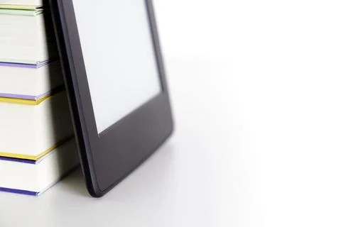 Corner of a stack of books and an electronic reader with a blank screen Stock Photos