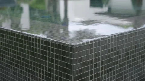 Corner of tiled structure pool with water flowing over edge. Square tiles Stock Footage 295551644