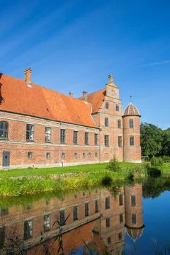 Corner tower of the historic castle reflected in the water in Rosenholm Foto stock