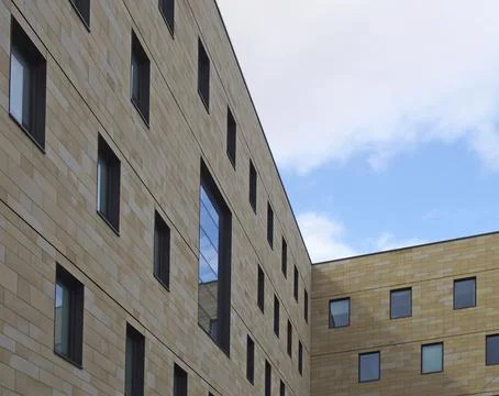 A corner view of a modern stone building with geometric repeating pattern of Stock Photos