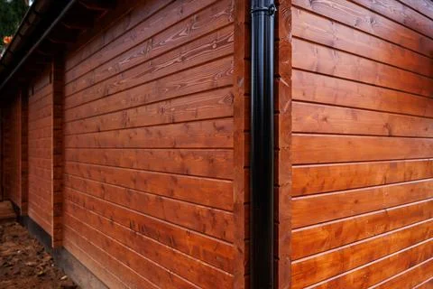 Corner view of stained timber cladding with matte black downpipe Stock Photos
