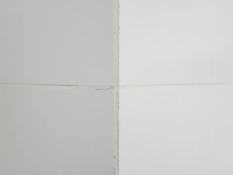 The corner of the wall is lined with white glossy ceramic tiles Stock Photos