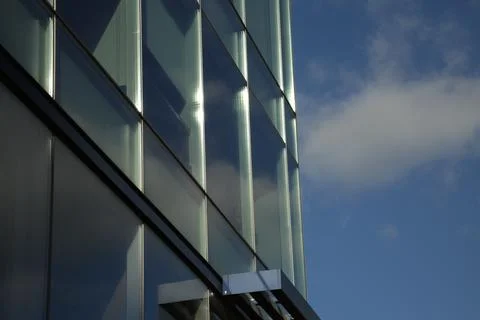 Corner of windowed sky scraper with a blue cloudy sky Foto stock