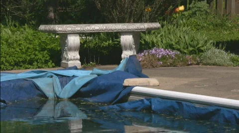 Corner of winterized pool with tarp and stone bench Stock Footage 544953
