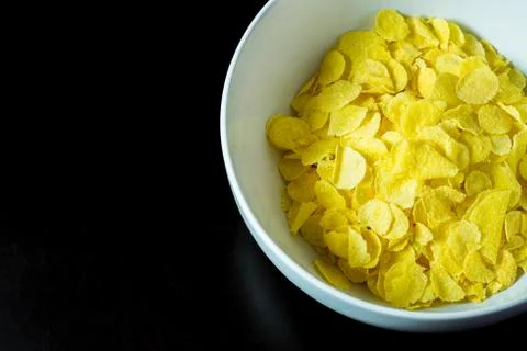 Cornflakes in bowl on black table Stock Photos