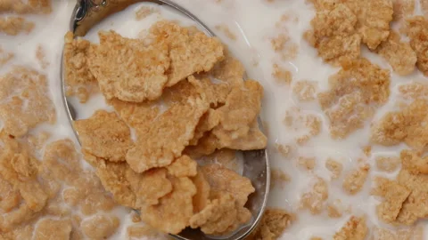 Cornflakes cereal and spoon turning on table 库存影片 162591099