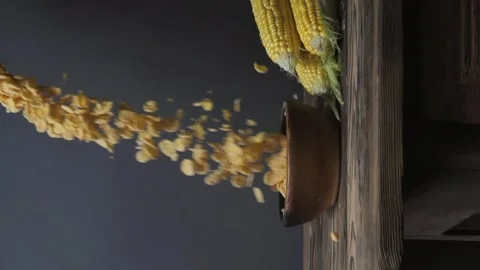 Cornflakes fall into a bowl on a wooden table. ears of corn lie nearby. Stock Footage 259203108