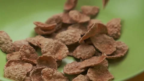 Cornflakes fall from top to bottom into a green plate, top view. Healthy cereal Stock Footage 147739743