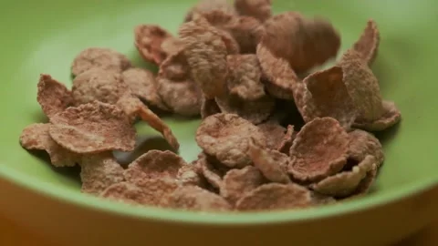 Cornflakes fall from top to bottom into a green plate, top view. Healthy cereal Stock Footage 148032089