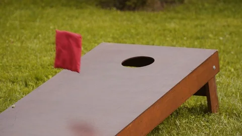 Cornhole. Game on green grass, throw red and blue bags, hit target Stock Footage