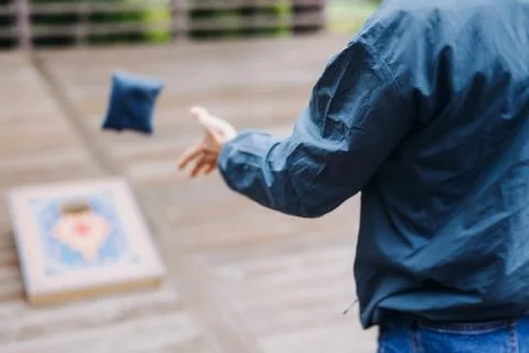 Cornhole game set, process of throwing bean bags, female girl tossing bean .. Фото