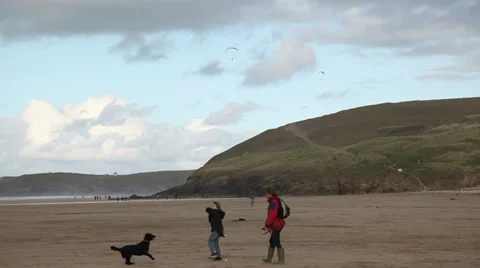 Cornish coast two poeple dog walking on a beach Stock Footage 33956191