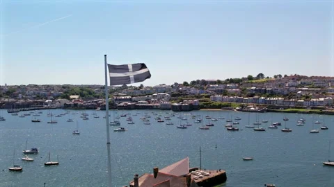 Cornish flag flying in slow motion over a harbor filled with boats, with a Stock Footage 285581489