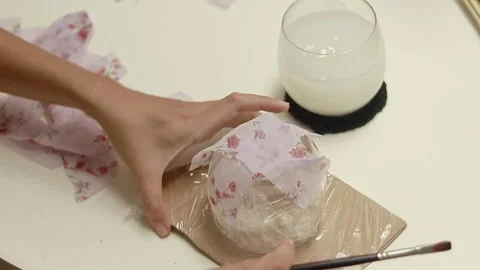 Cornstarch glue being brushed on a mold and attaching recycled floral fabric Video stock 312137546