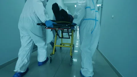 Coronavirus pandemic concept. Physicians in protective suits carry a man on Vídeo Stock 135436302