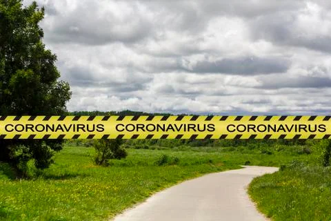 Coronavirus warning tape with empty park on the background. Covid-19 lockdown Stock Photos