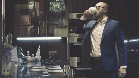 Corporate CEO drinks coffee in luxury apartment kitchen Stock Footage 105020401