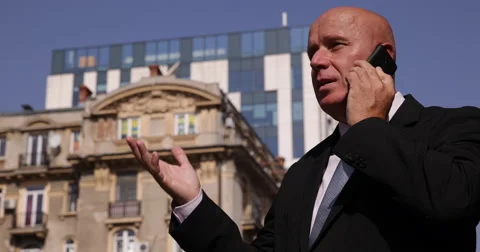 Corporate Manager Outside Office Talking Serious to Mobile Phone Financial Deal Stock Footage 66907039