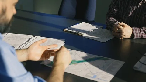 Corporate Meeting Between Men at a Table, Talking With Hands, Desk of Papers Stock Footage 122291459