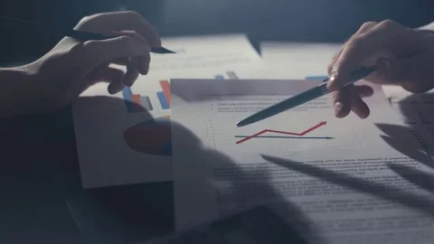 Corporate startup team having a progress meeting looking at printed data and Видео 72809775