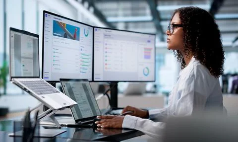 Corporate Trainer Analyzes Employee Progress Charts On Dual Laptop Screens. Stock Photos