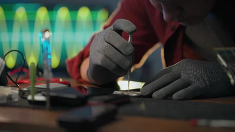 To correct. An electronic technician wearing protective gloves focuses on us Stock Footage 278246307