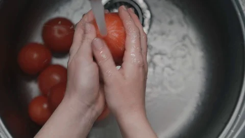 Correct way to wash vegetables, hands are washed the tomatoes under water Stock Footage 129899192