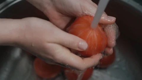Correct way to wash vegetables, hands are washed the tomatoes under water Stock Footage 129899293