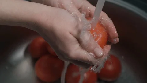 Correct way to wash vegetables, hands are washed the tomatoes under water Stock Footage 129899347