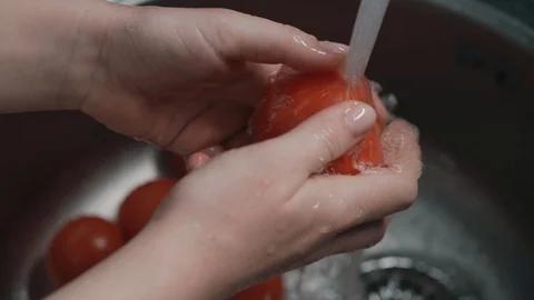 Correct way to wash vegetables, hands are washed the tomatoes under water Stock Footage 129899460