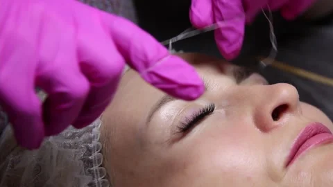 Correction and shaping of women's eyebrows in a beauty salon. eyebrow threading Stock Footage