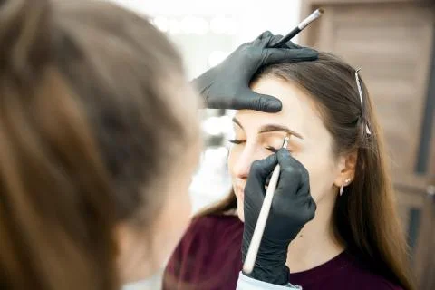 Correction and tinting eyebrows, master applies thread to woman on brow 스톡 사진