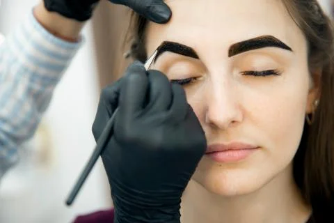 Correction and tinting eyebrows, master applies thread to woman on brow Foto stock