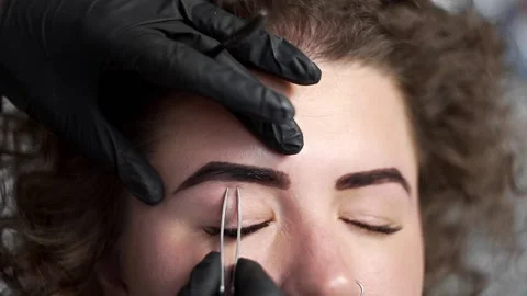 Correction of eyebrows shape by depilation by tweezers at the beauty salon Stock Footage 90310446