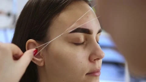 Correction eyebrows shape, removing unwanted hair using thread, threading brows Stock Footage 173408186