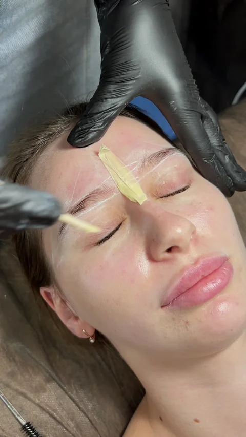 Correction of a shape of eyebrows with hot wax. Brow master applying wax on the Stock Footage 280339603