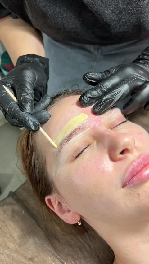 Correction of a shape of eyebrows with hot wax. Brow master applying wax on the Stock Footage 280339632
