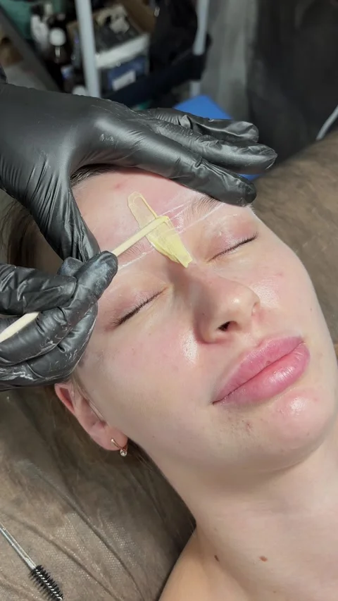 Correction of a shape of eyebrows with hot wax. Brow master applying wax on the Stock Footage 282697645