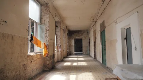 Corridor of abandoned ruined building inside which refugees now live as shelter Stock Footage 242438203