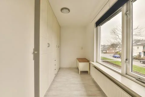 A corridor with a large window and a small table Stock Photos
