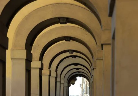 Corridor with rows of columns and arc in sunlight, Florence Stock Photos