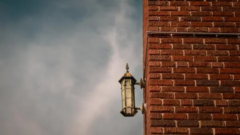 Corroded copper lantern mounted on brick wall with cloudscape Stock Photos