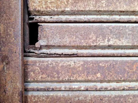 Corroded metal shutter panel with rusted texture and structural damage for .. Stock Photos